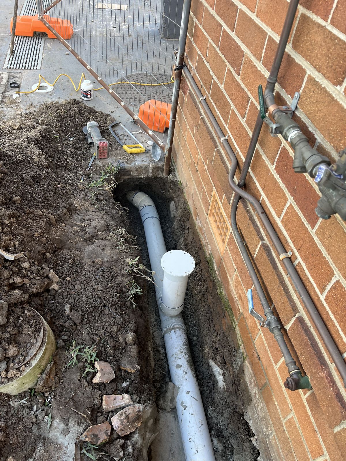 Sewer drain replacement showing new PVC pipework in an excavated trench, replacing a collapsed terracotta line