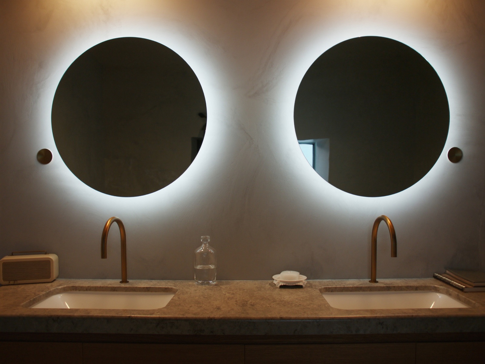 Double vanity with backlit round mirrors and brass tapware