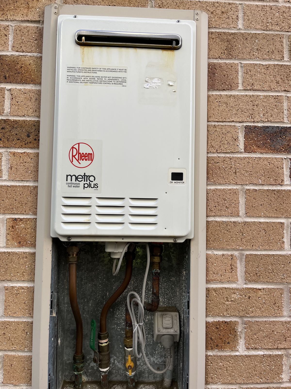 Rheem Metro Plus continuous flow gas hot water unit installed on the exterior brick wall of a Western Sydney home