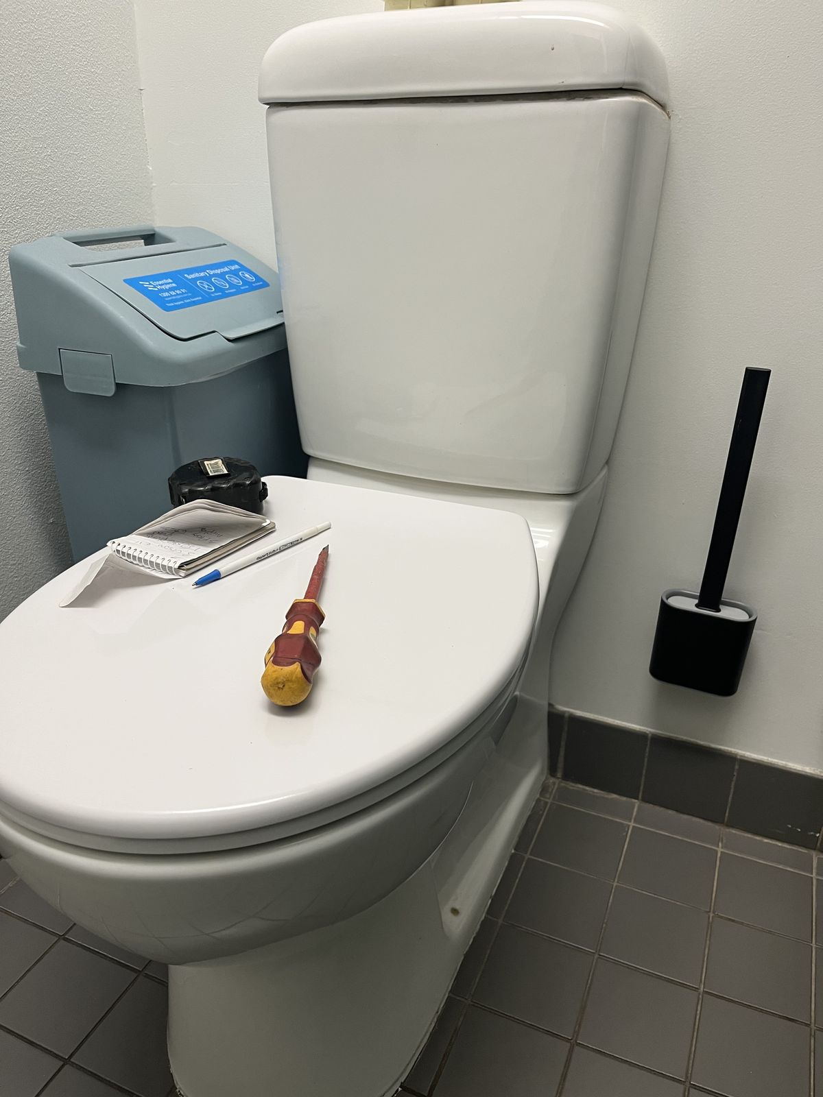 Toilet repair in progress with screwdriver and parts on the cistern lid - emergency same-day callout