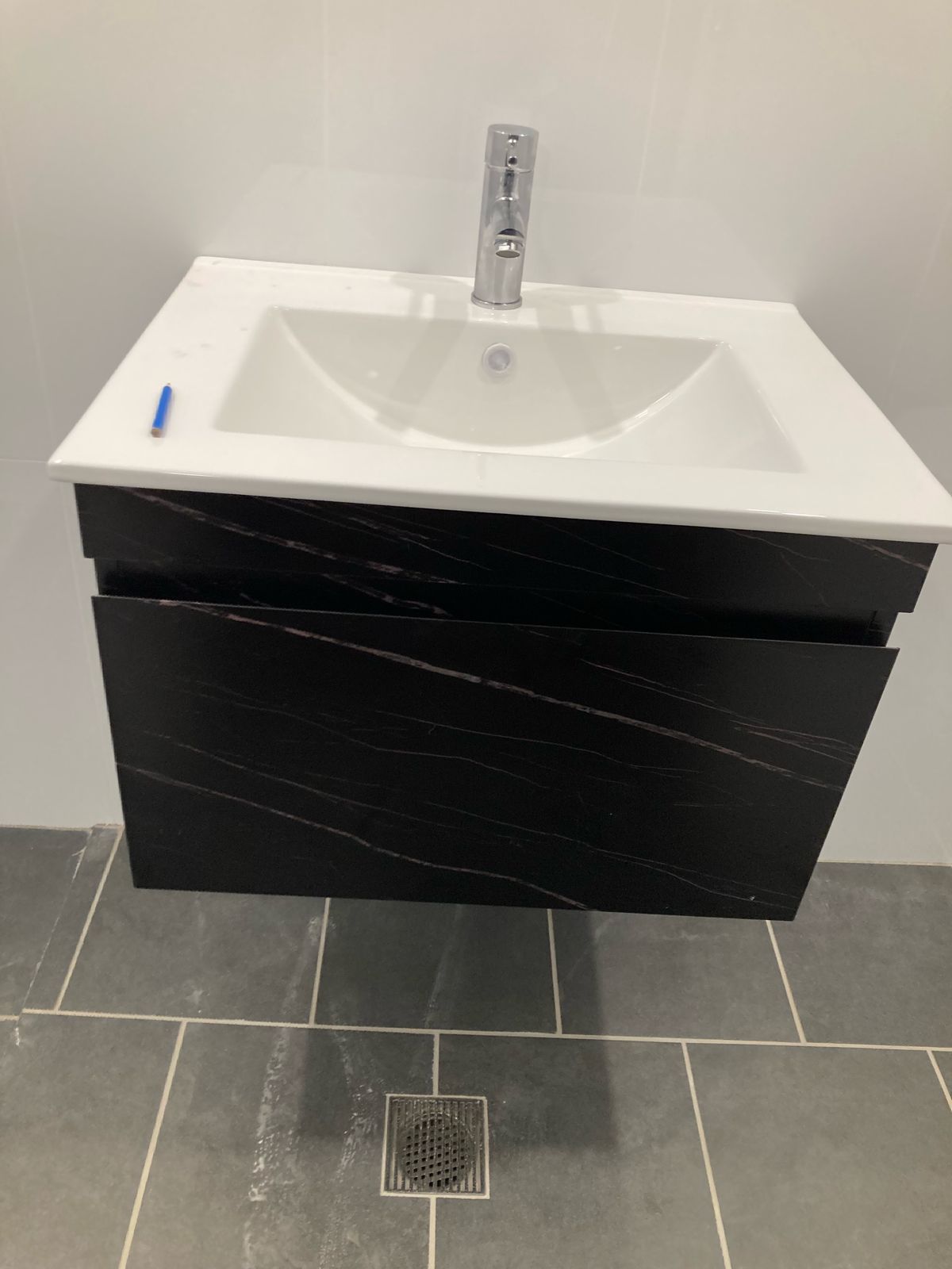 Wall-hung vanity with black marble cabinet completed in Auburn